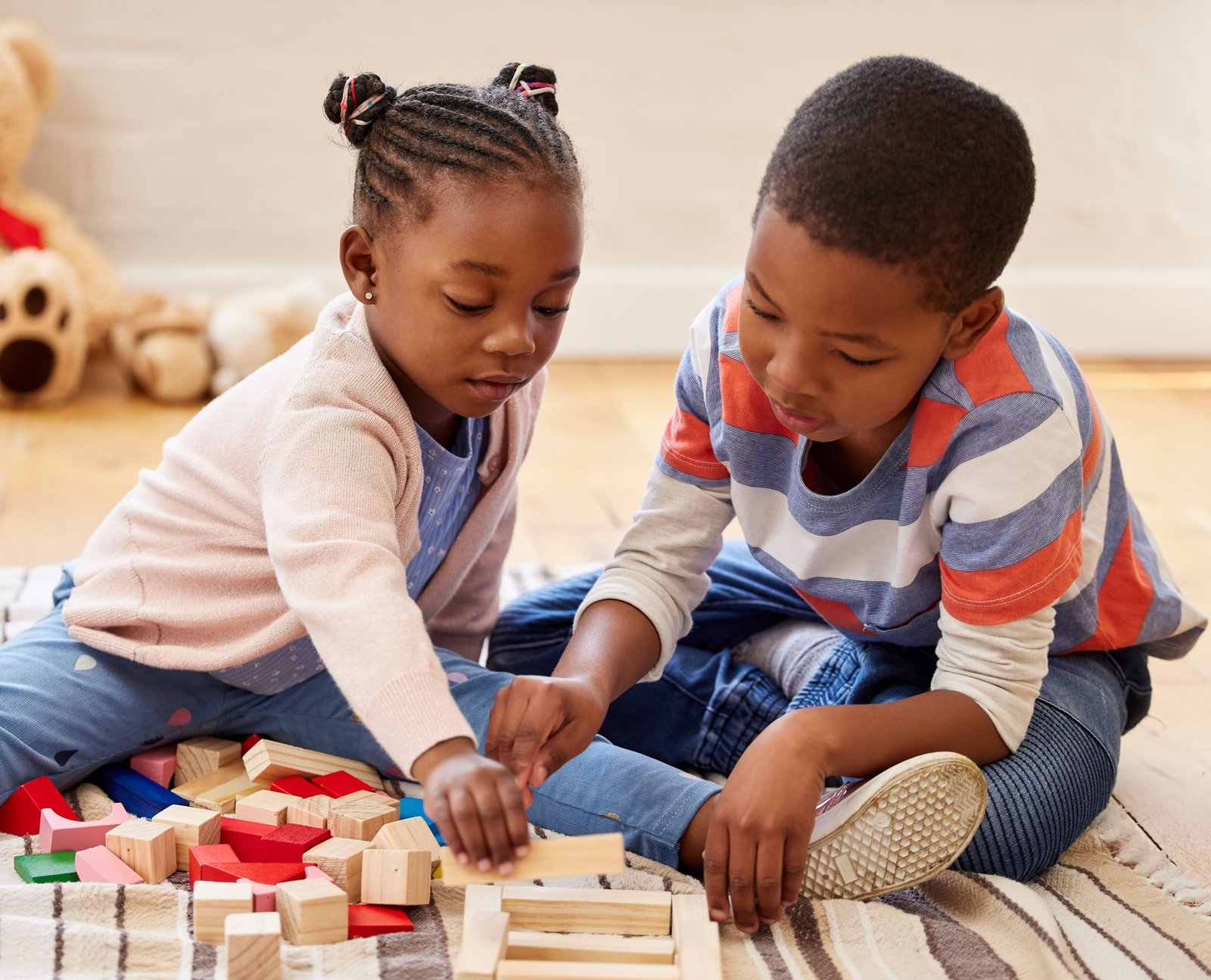 Two young children playing together with building blocks
